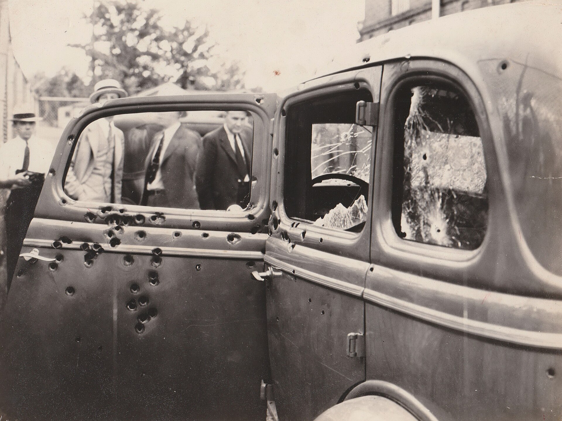 The Ford V8 after the ambush — bullet holes visible across the door panels