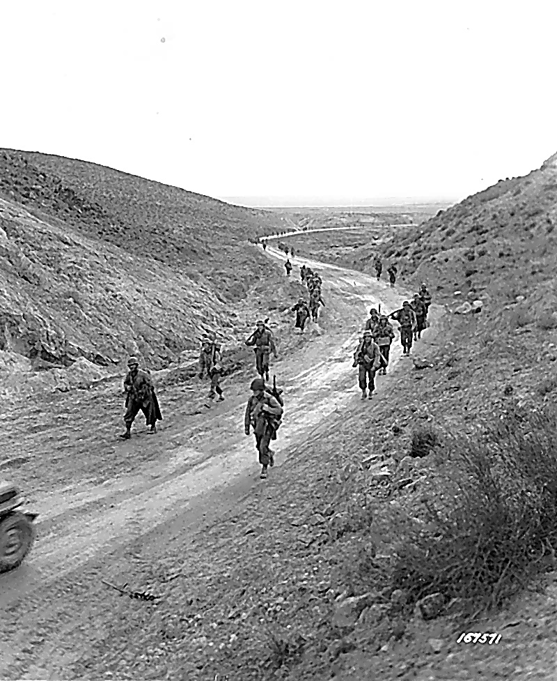 American troops march through Kasserine Pass after its recapture, February 26, 1943.
